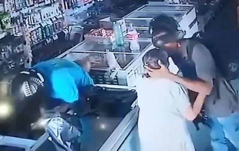 Aptekə silahlı basqın edən soyğunçu yaşlı müştərini sakitləşdirir