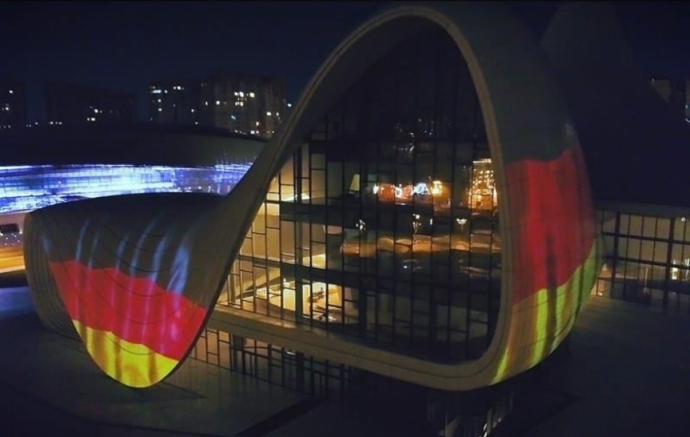 Heydar Aliyev Center für Deutschland mit Lichtstrahlen in Schwarz-Rot-Gelb beleuchtet